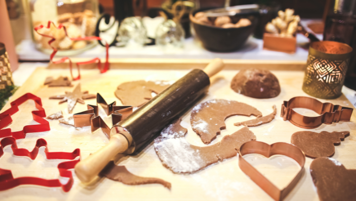 Weihnachtsbäckerei: Tisch mit Ausstechförmchen, Plätzchenteig, einem Nudelholz und bereits ausgestochenen Plätzchen.